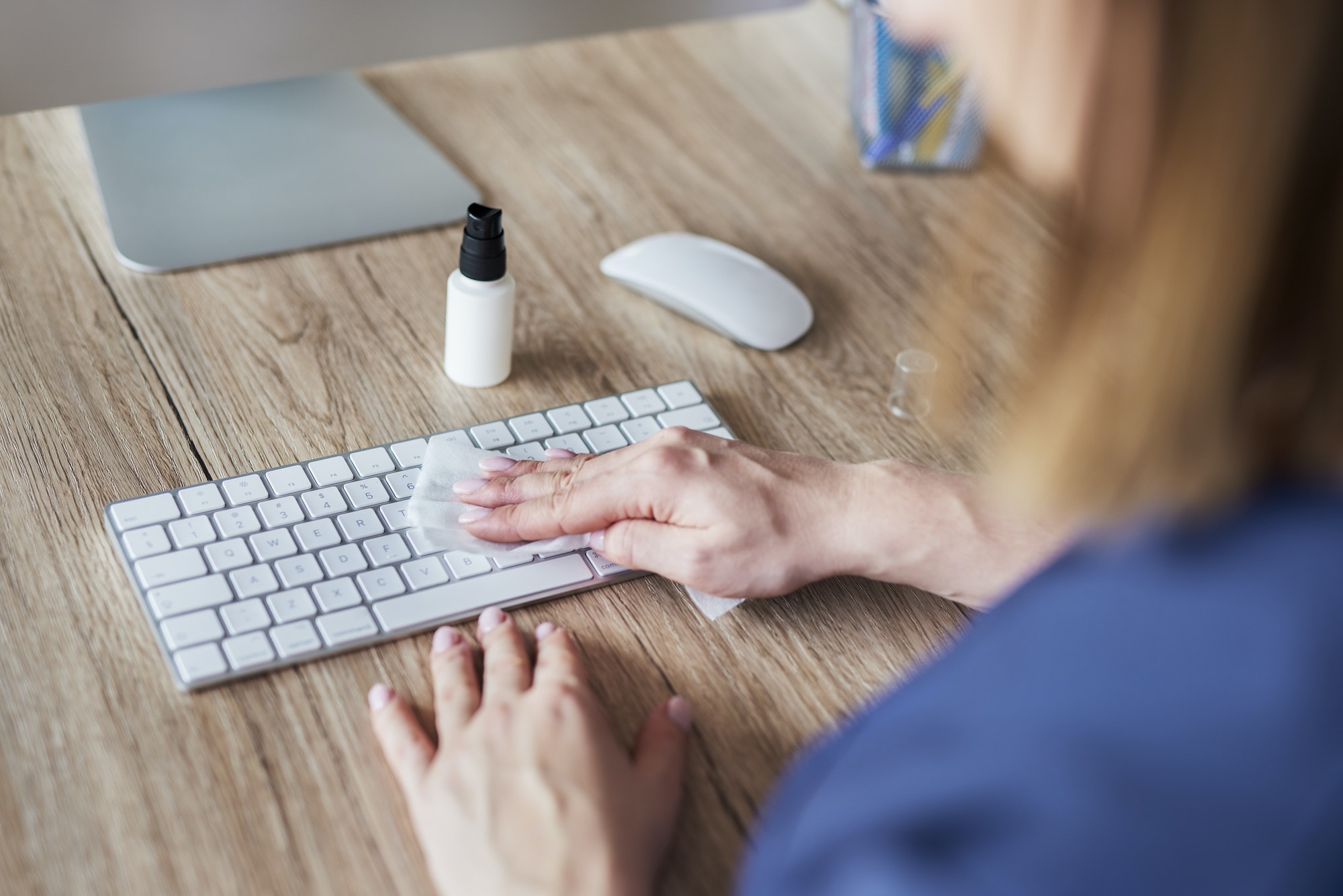 High angle view of woman cleaning keyboard in the office